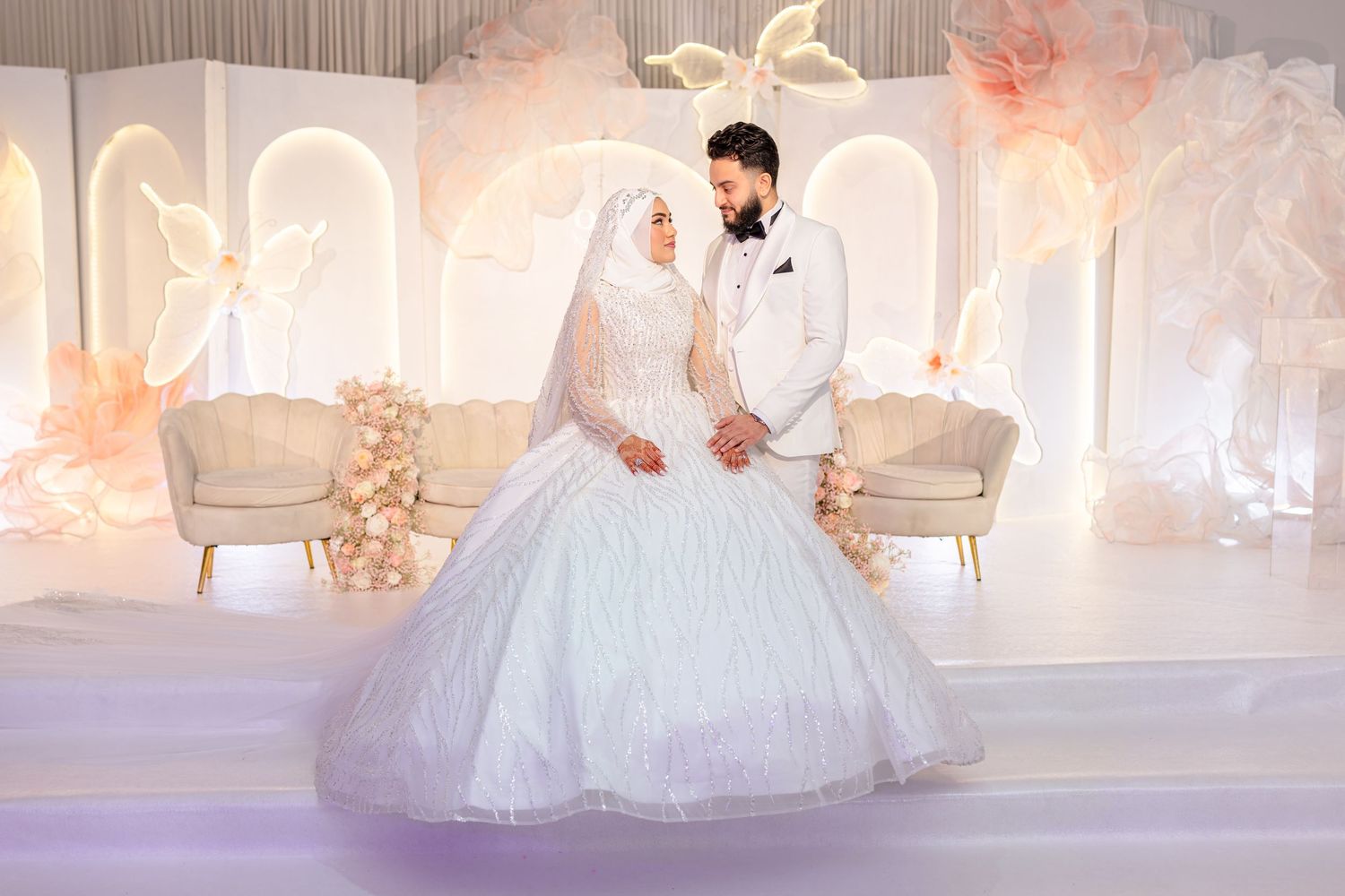 A series of wedding reception photos showing elegant decor with white and pink lighting in a luxurious ballroom setting.