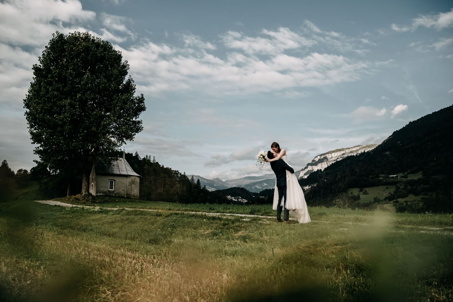 Hochzeitspaar auf Wiese bei Bonaduz Graubünden Schweiz – natürliche, emotionale Hochzeitsfotos mit Flims Bergen im Hintergrund von Mediasqua