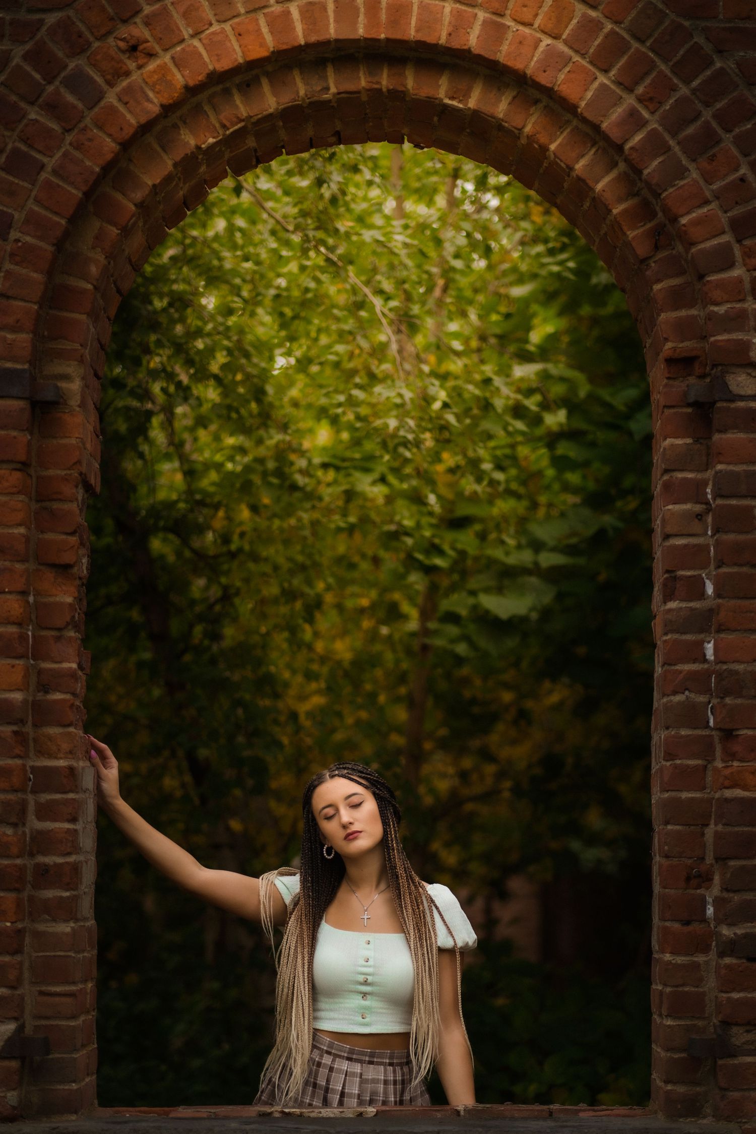 An arched brick doorway frames a dreamy outdoor garden scene with lush green foliage in the background.