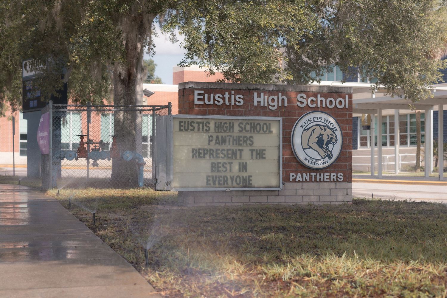 Eustis High School sign displaying Panthers motto in Florida, with school building and trees visible in background.