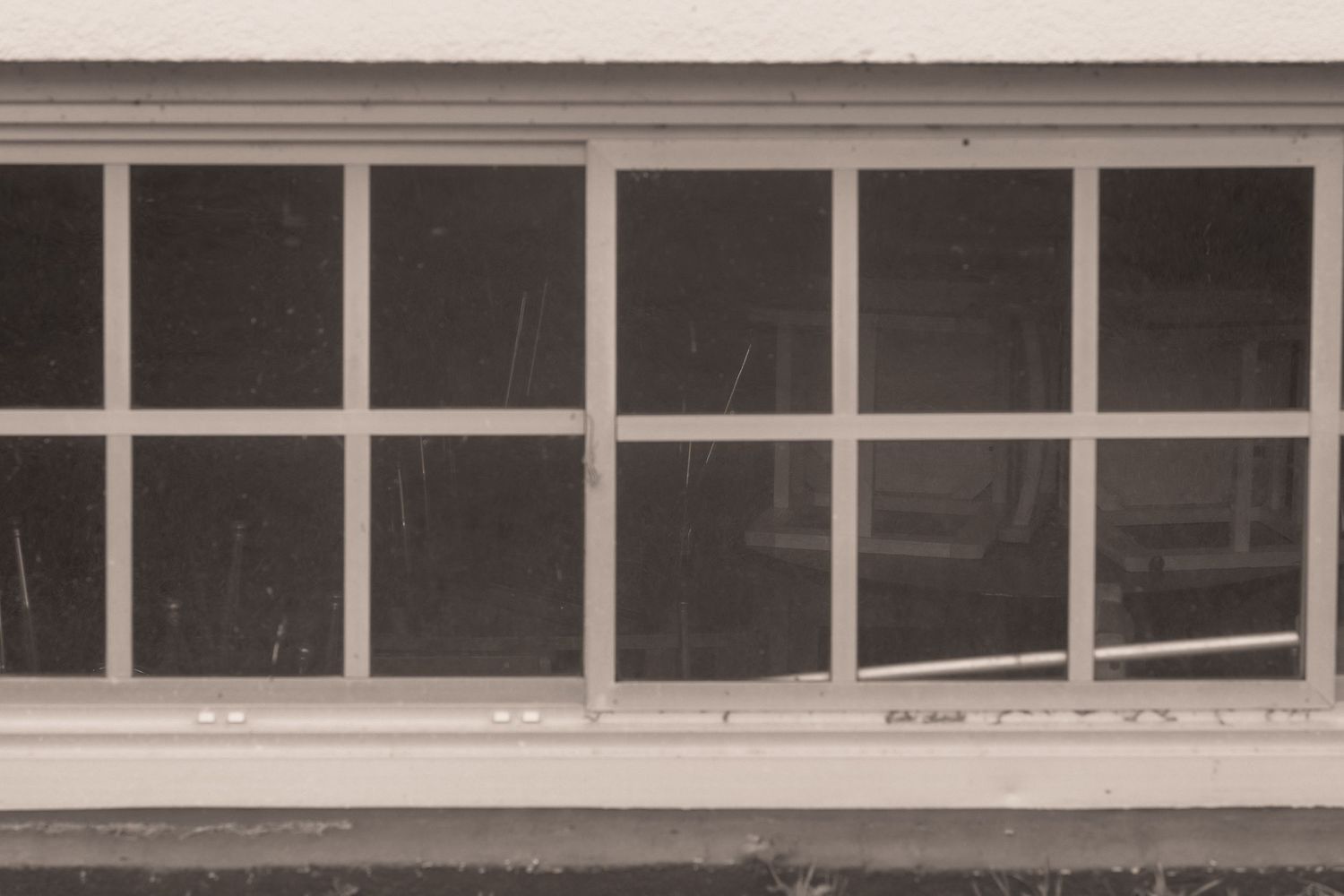 Vintage sepia-toned photo of a large multi-pane window on a white building exterior.