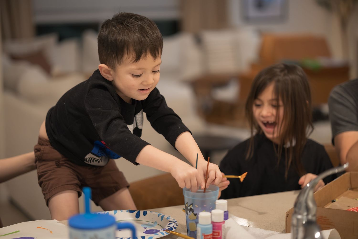 Children focused on activity at table in bright indoor space.