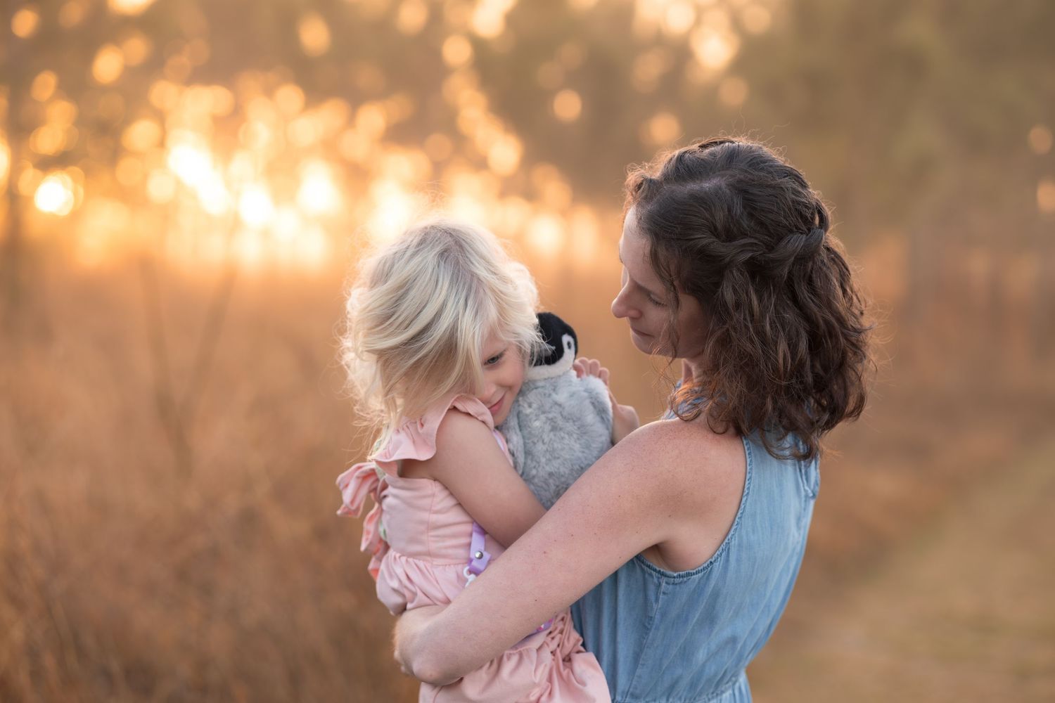Two people share a tender embrace in a sunlit outdoor setting during golden hour.