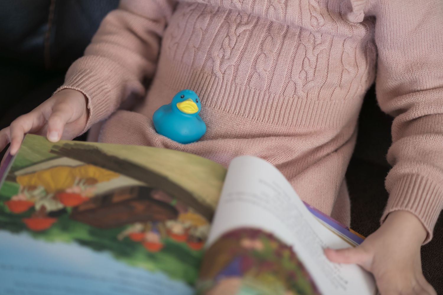 A person in a pink sweater uses colorful play dough and toys to engage in sensory play activities.