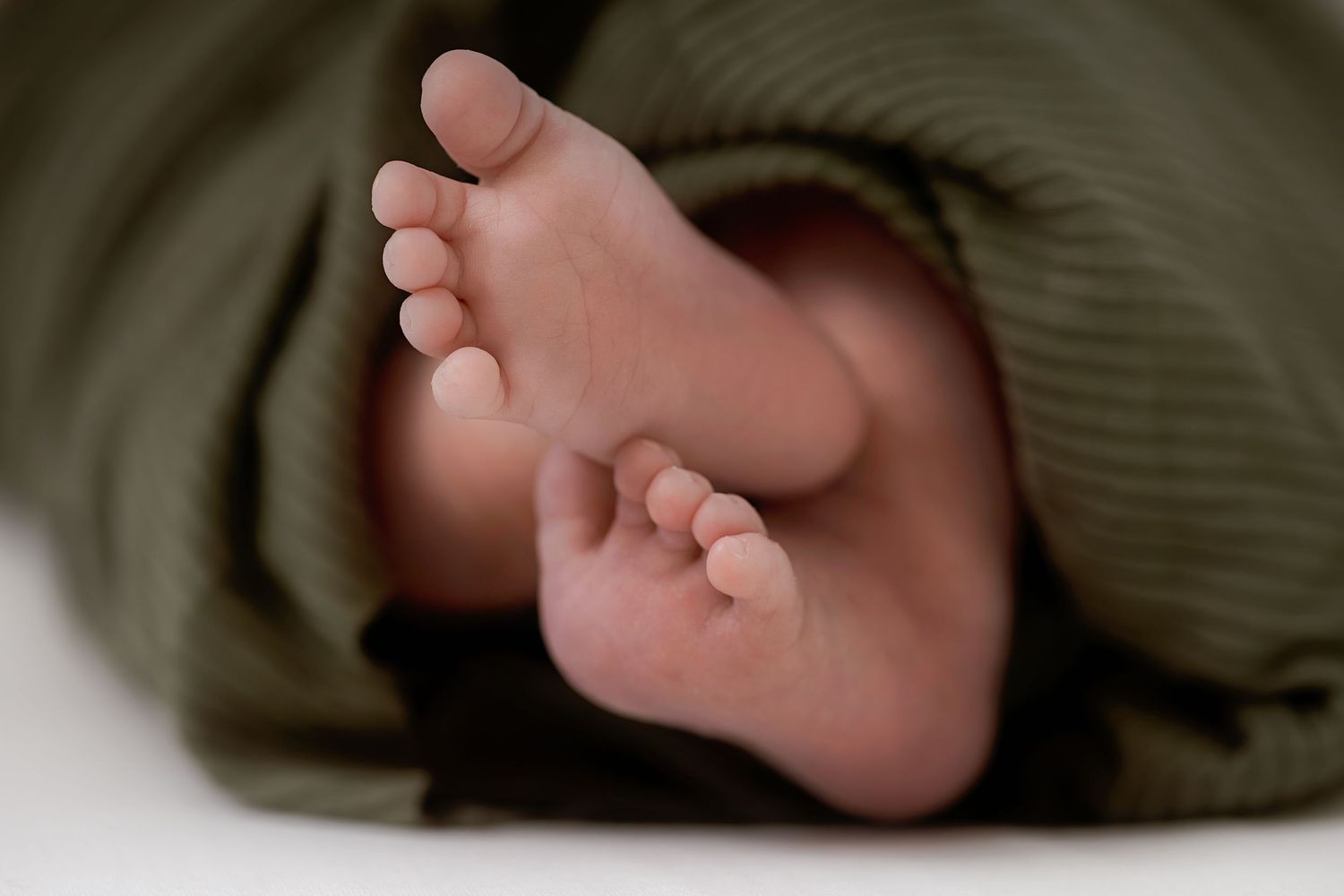 A row of baby feet lined up in a series showing different angles and positions against a dark background.