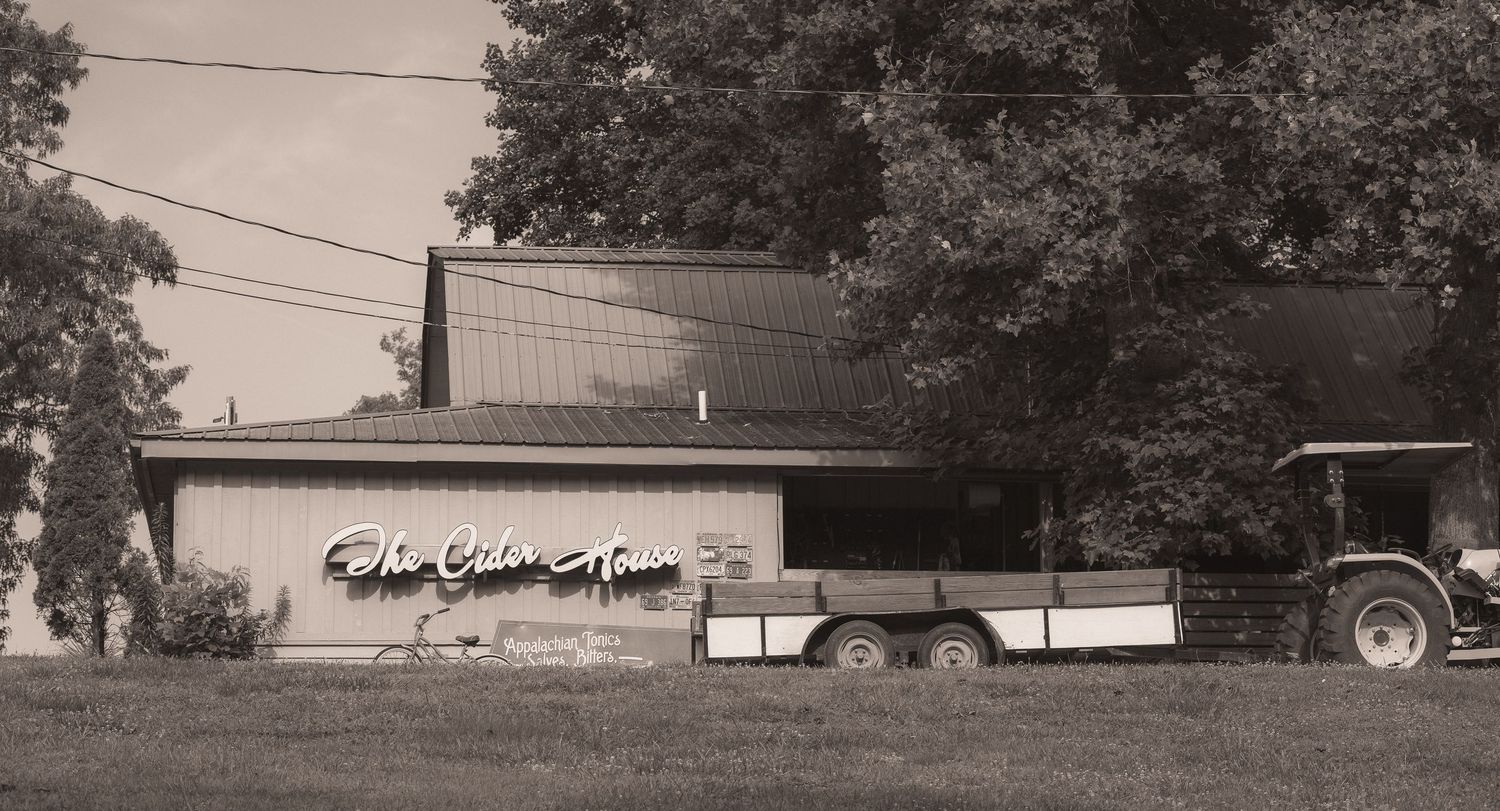 Vintage black and white photo of The Golden House restaurant with a trailer and tractor parked outside.