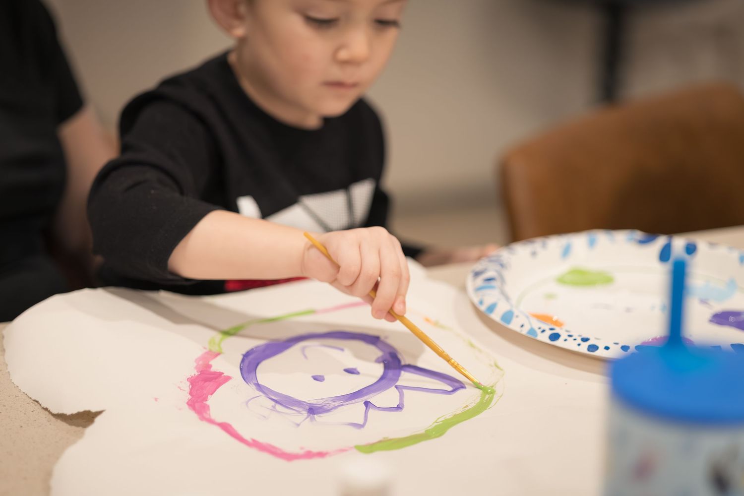 Child focused intently on drawing or coloring at a table.