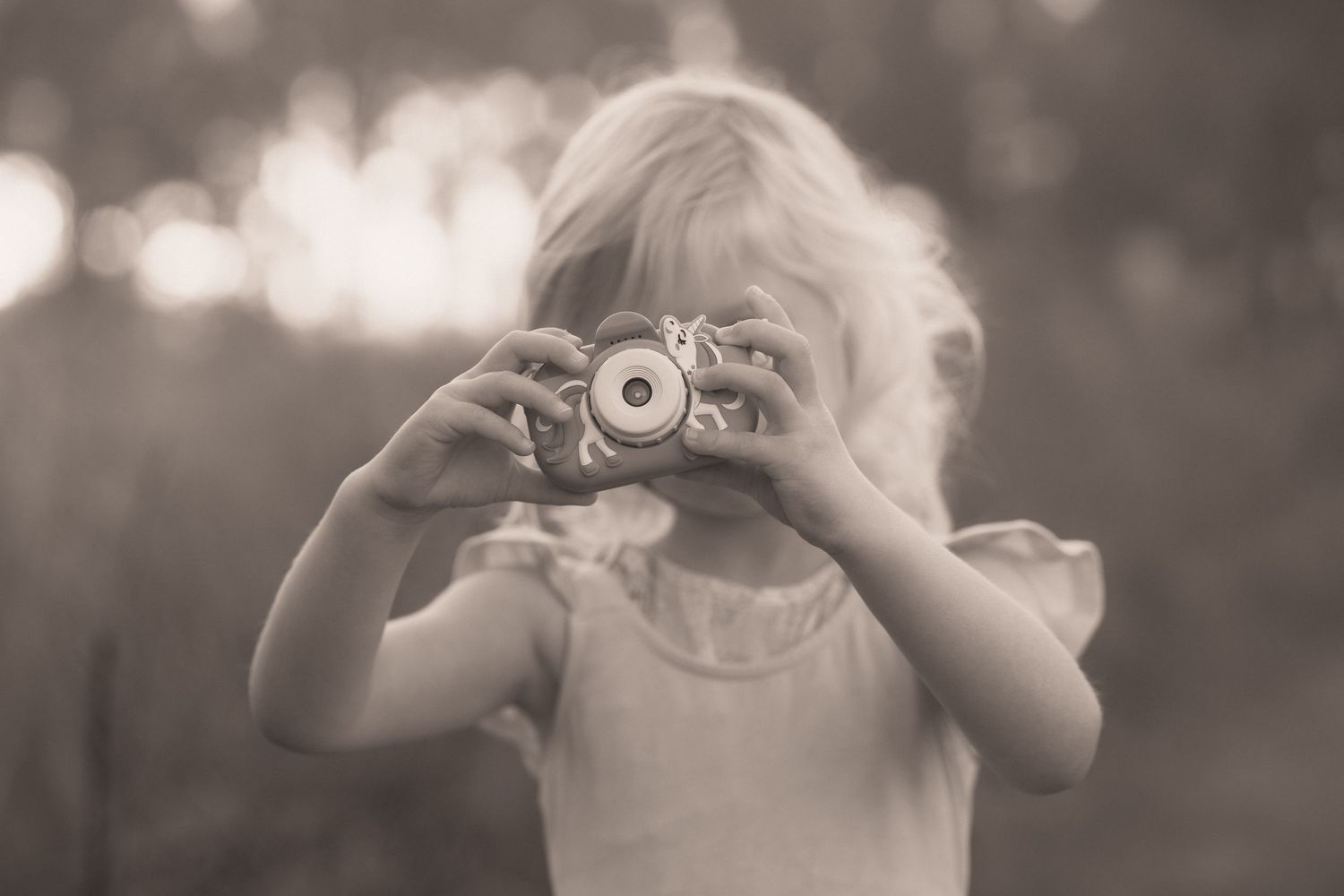 A sequence of black and white photos showing a child holding a vintage camera up to their eye to take a picture.