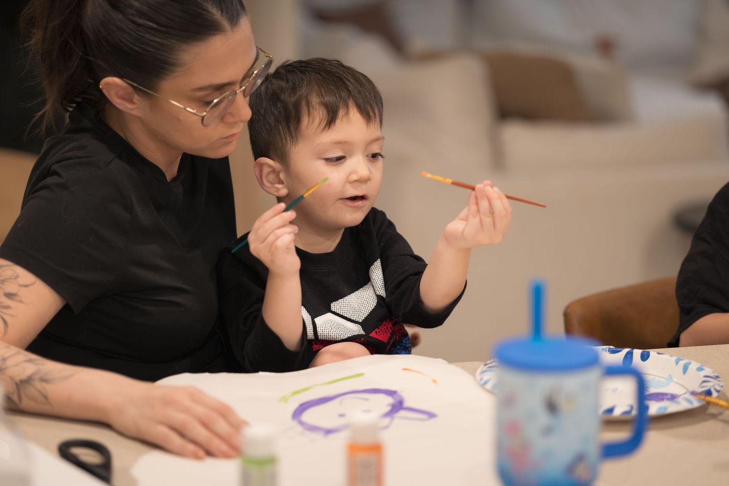 Adults and child engaged in an art activity with colorful supplies.