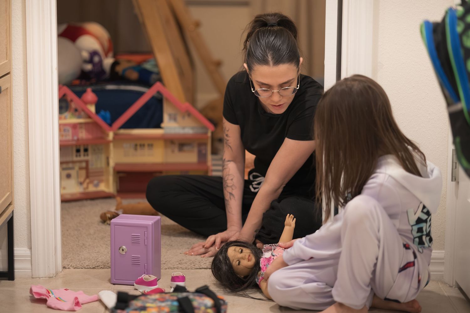 People sit on the floor playing with toys and games in a home setting.
