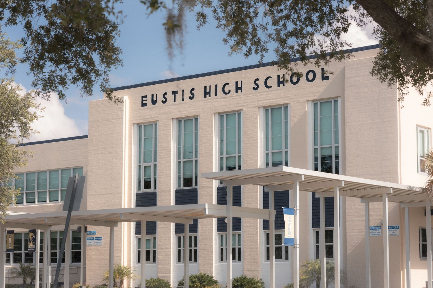 Eustis High School building exterior featuring modern architecture, large windows, and the school name displayed prominently on the facade.