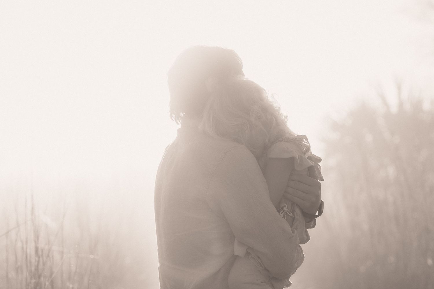 A silhouetted figure stands in foggy winter landscape holding a camera against a misty white background.