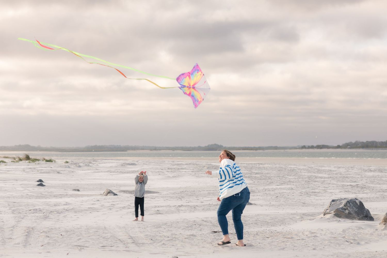 A series of beach scenes showing people walking along a misty shoreline on an overcast day.