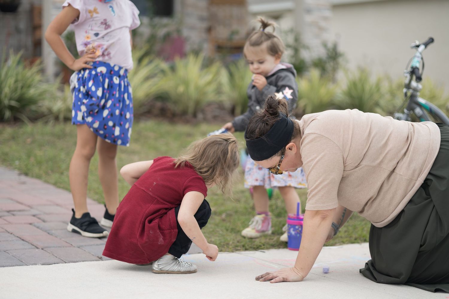 A group gathers on a sidewalk to observe something interesting on the ground together.