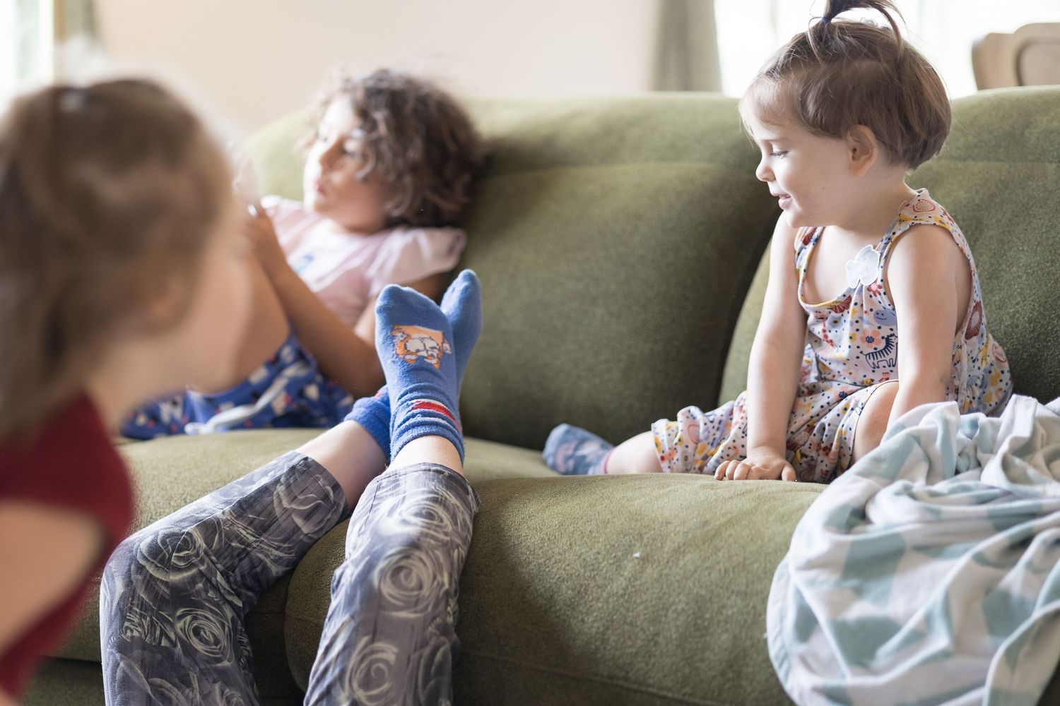 A sequence of photos showing a baby sitting on a green couch while reading or looking at a book.