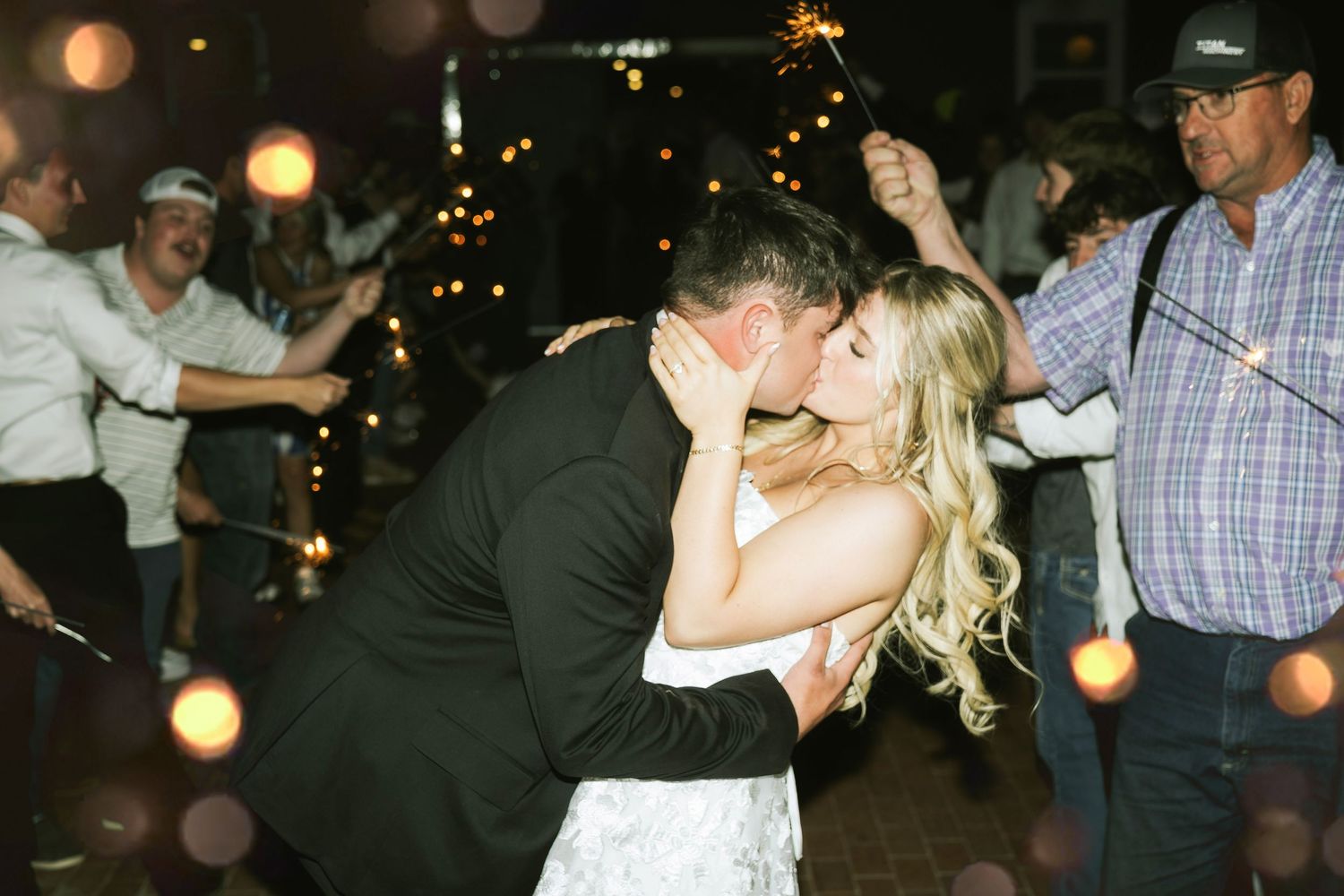 couple kissing at wedding sparkler exit