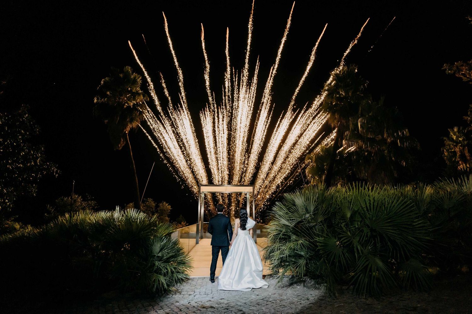 A backlit wedding ceremony setup with illuminated wooden beams at dusk.