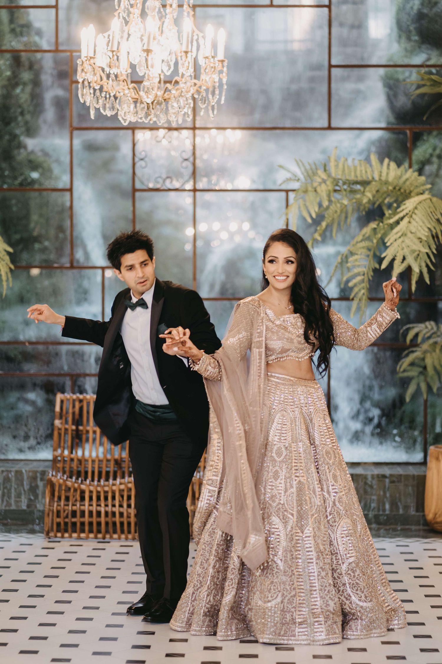 A couple dances together in an elegant ballroom with crystal chandeliers and ornate decor.