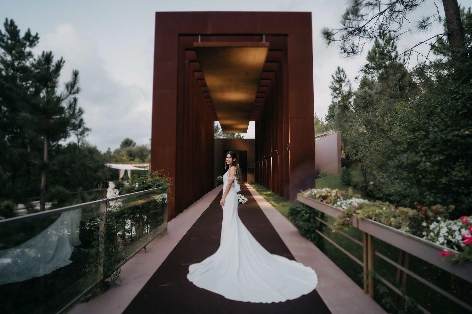 Dramatic bridal portrait in long train dress inside modern architectural corridor.
