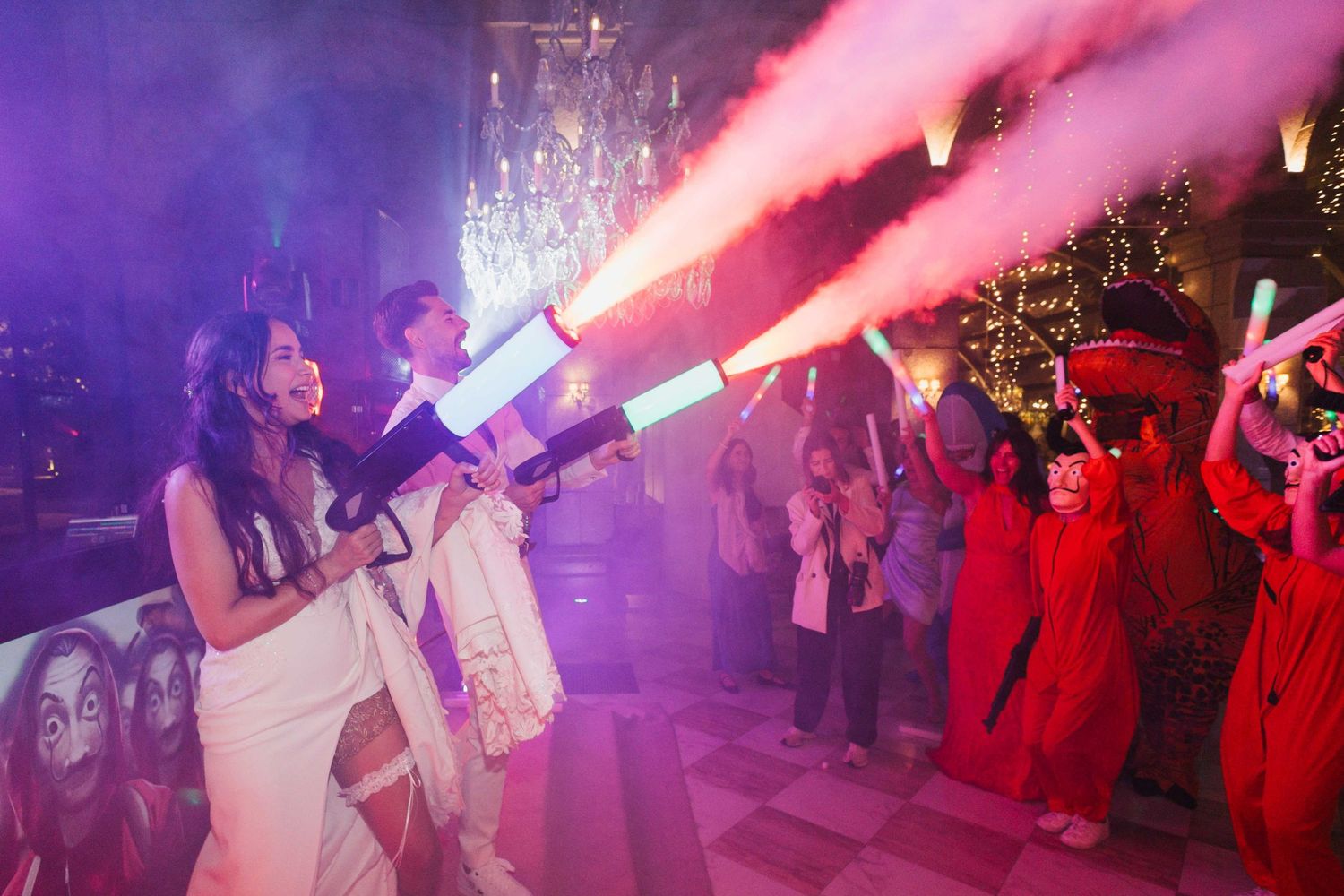 A nightclub scene with pink and purple lighting illuminates people dancing and celebrating on a crowded dance floor.