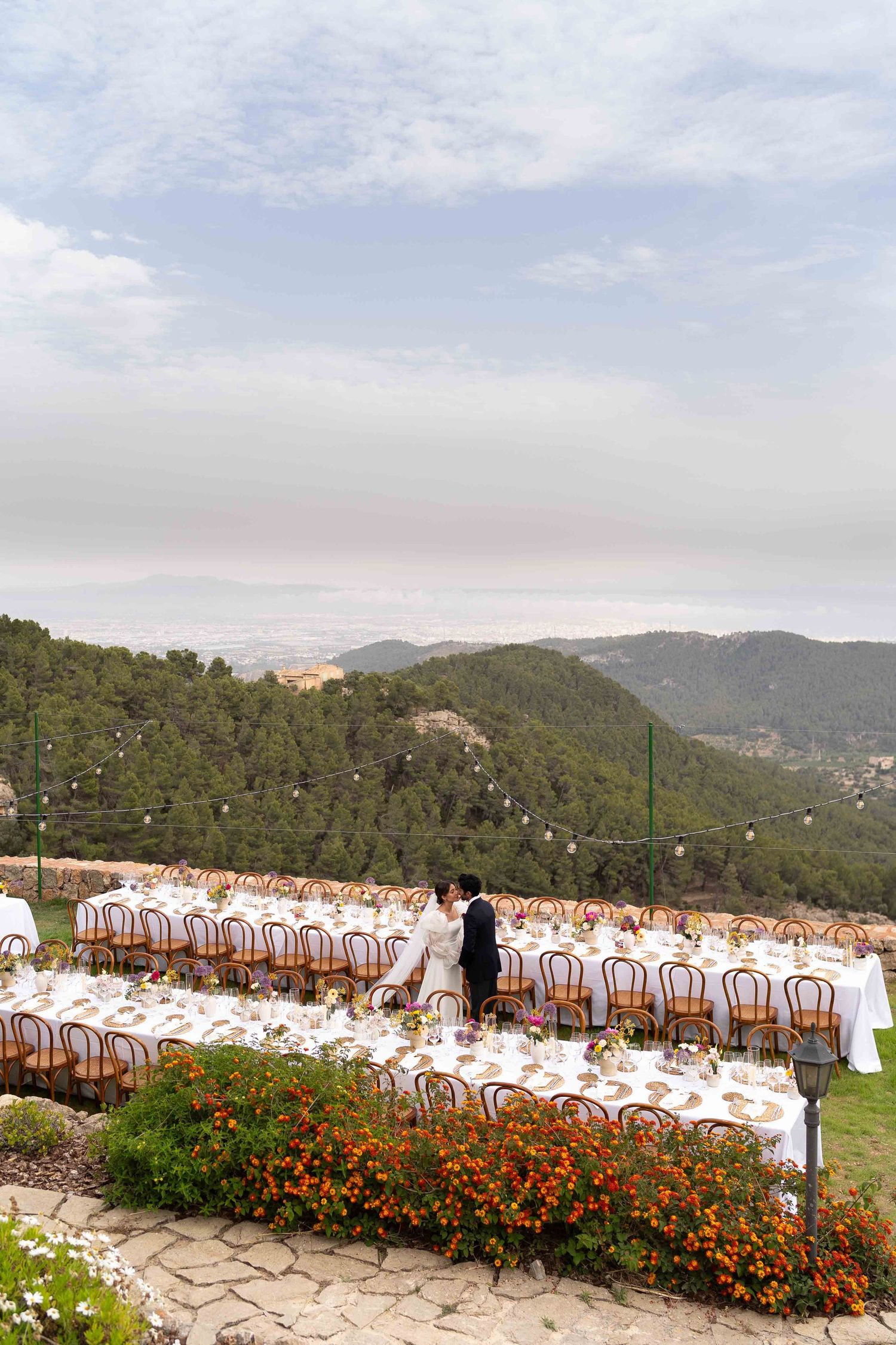 Outdoor wedding reception setup with tables and chairs overlooking mountain views.