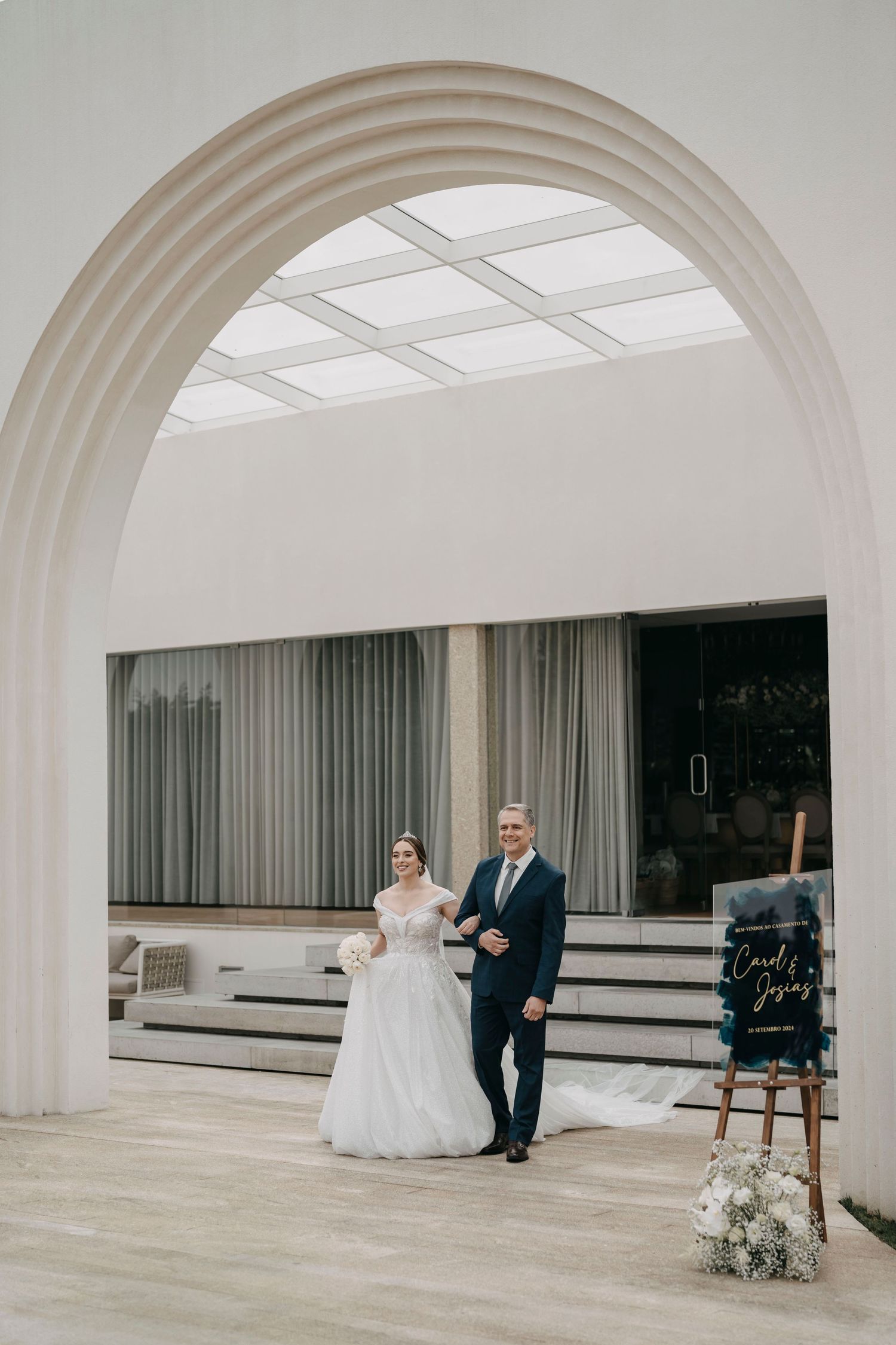 A wedding ceremony setup in a modern white space with arched ceilings and minimal decor.