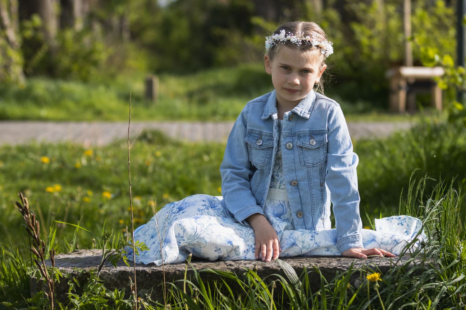 communie foto in kasteel van herkenrode. meisje van 7 jaar. Communicant met bloemen in het haar en blauw gebloemde jurk.