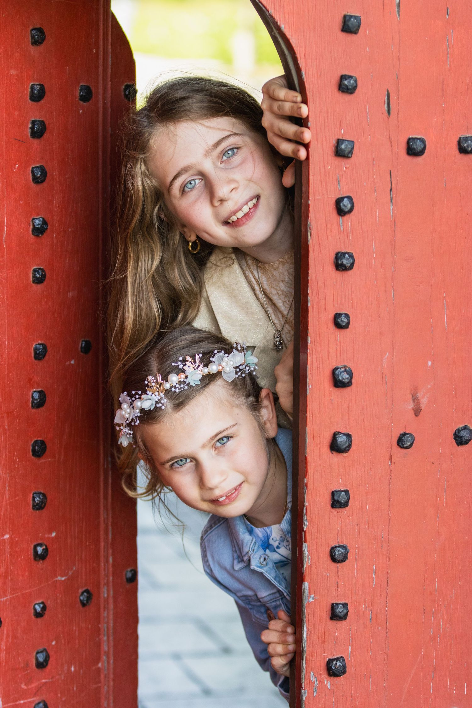 communie foto in kasteel van herkenrode. Grote zus met lange blonde haren. Communicant met bloemen in het haar en blauw gebloemde jurk.