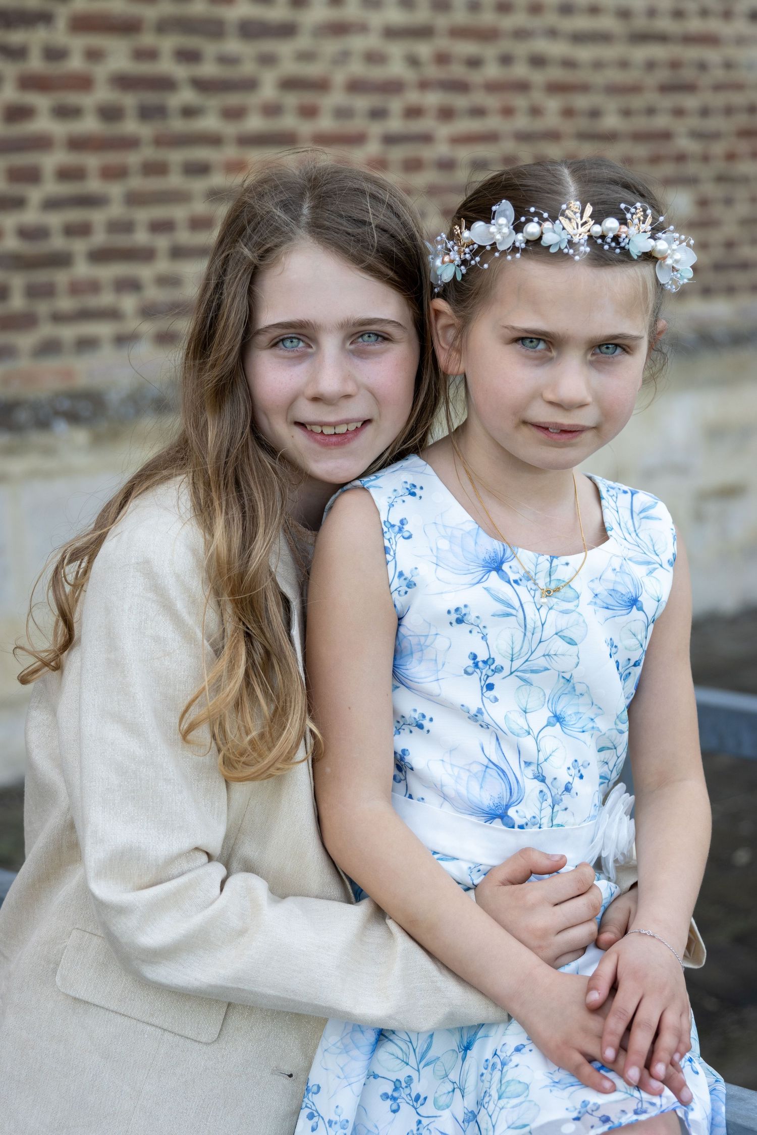 communie foto in kasteel van herkenrode. Grote zus met lange blonde haren. Communicant met bloemen in het haar en blauw gebloemde jurk.