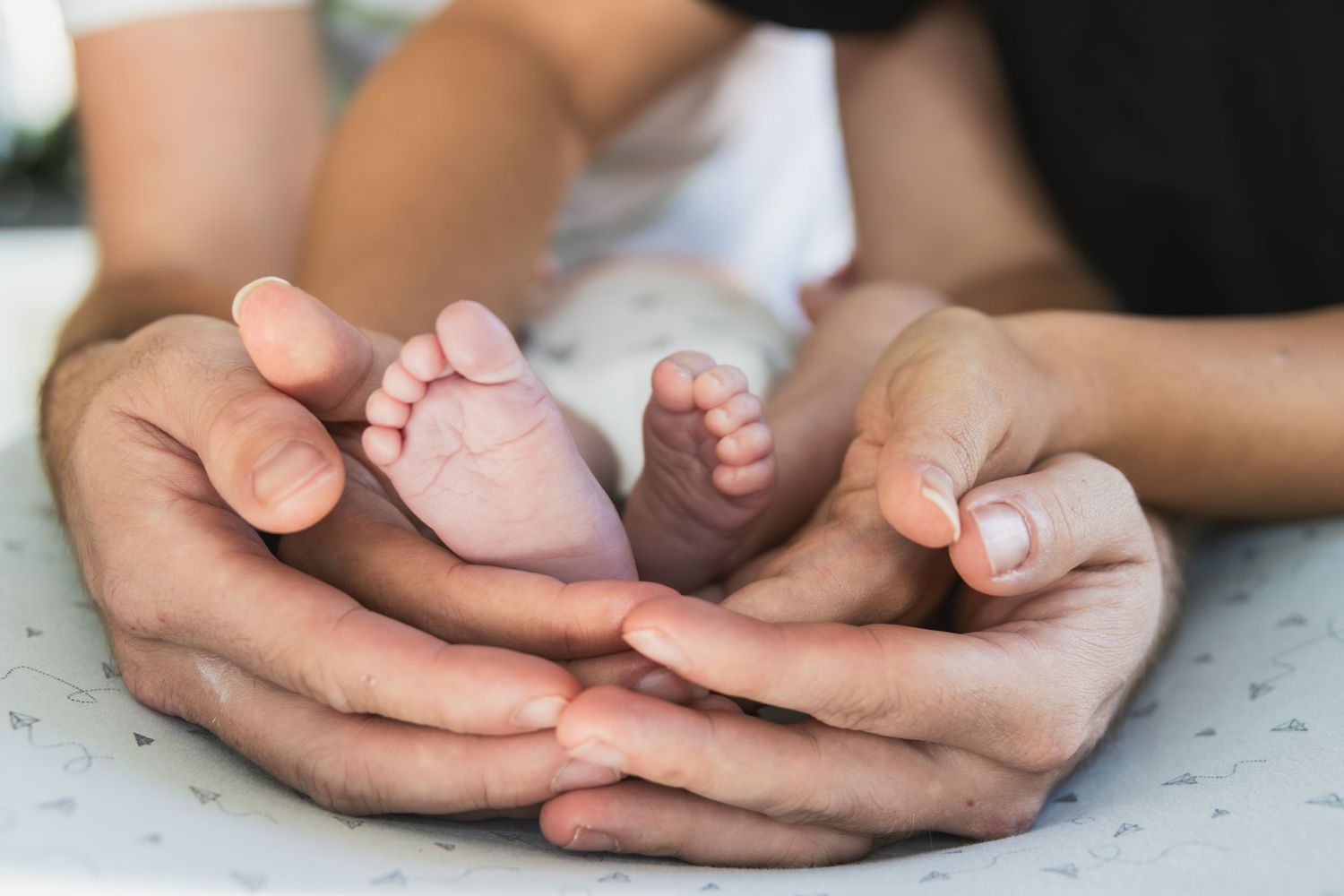 portret van de voetjes van een pasgeboren baby omringd door de armen en handen van mama en papa. newborn. shoot.