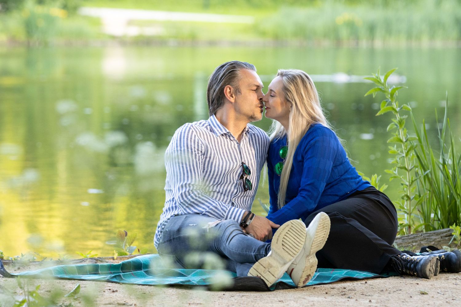 Een verliefd koppel. De vrouw met lange blonde haren en een blauwe trui kust de man met een blauw gestreept hemd. provinciaal domein