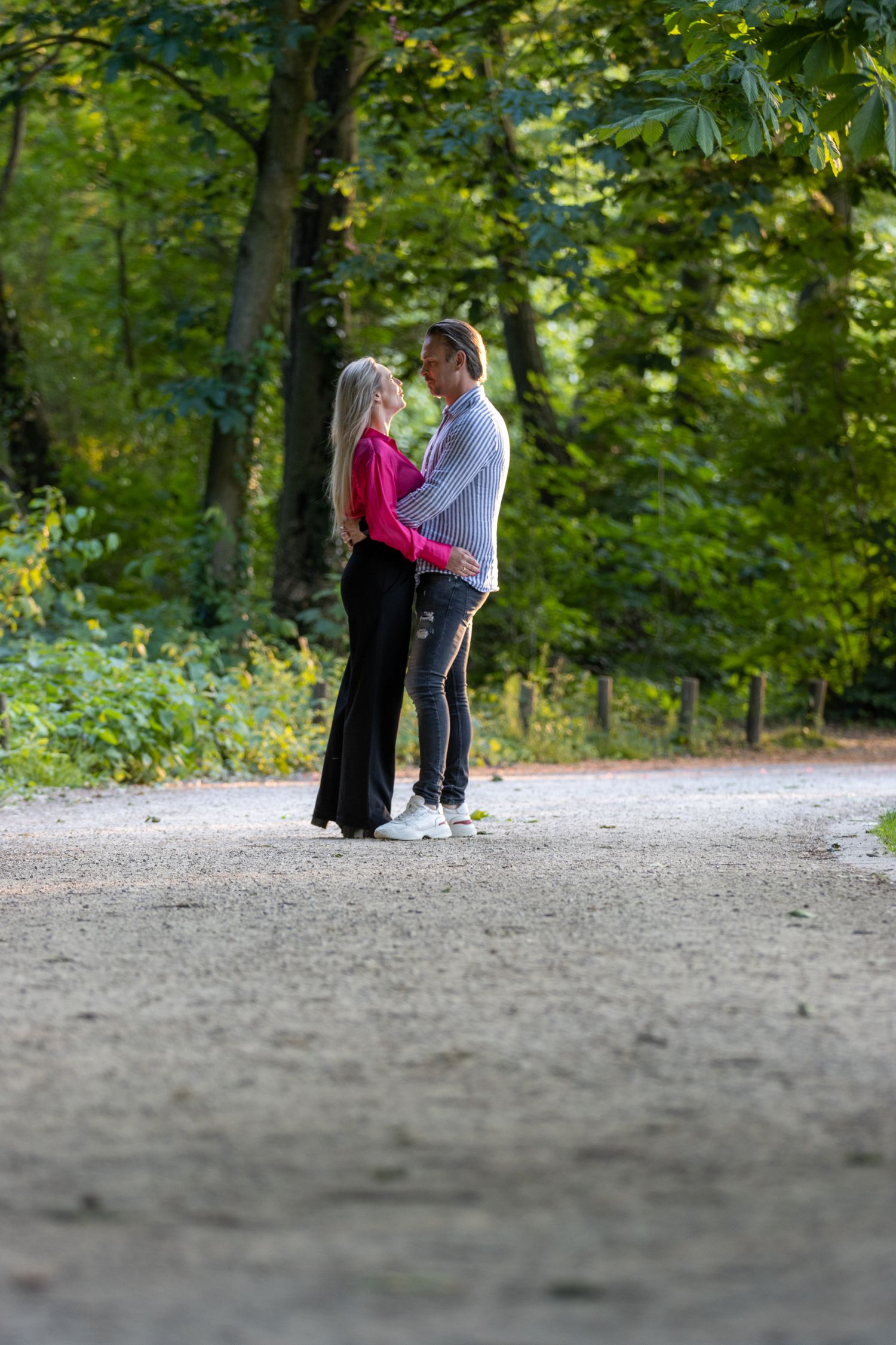 Koppel in het provinciaal domein van kessel-lo. Lange blonde haren, roze hemd. Bomen op de achtergrond