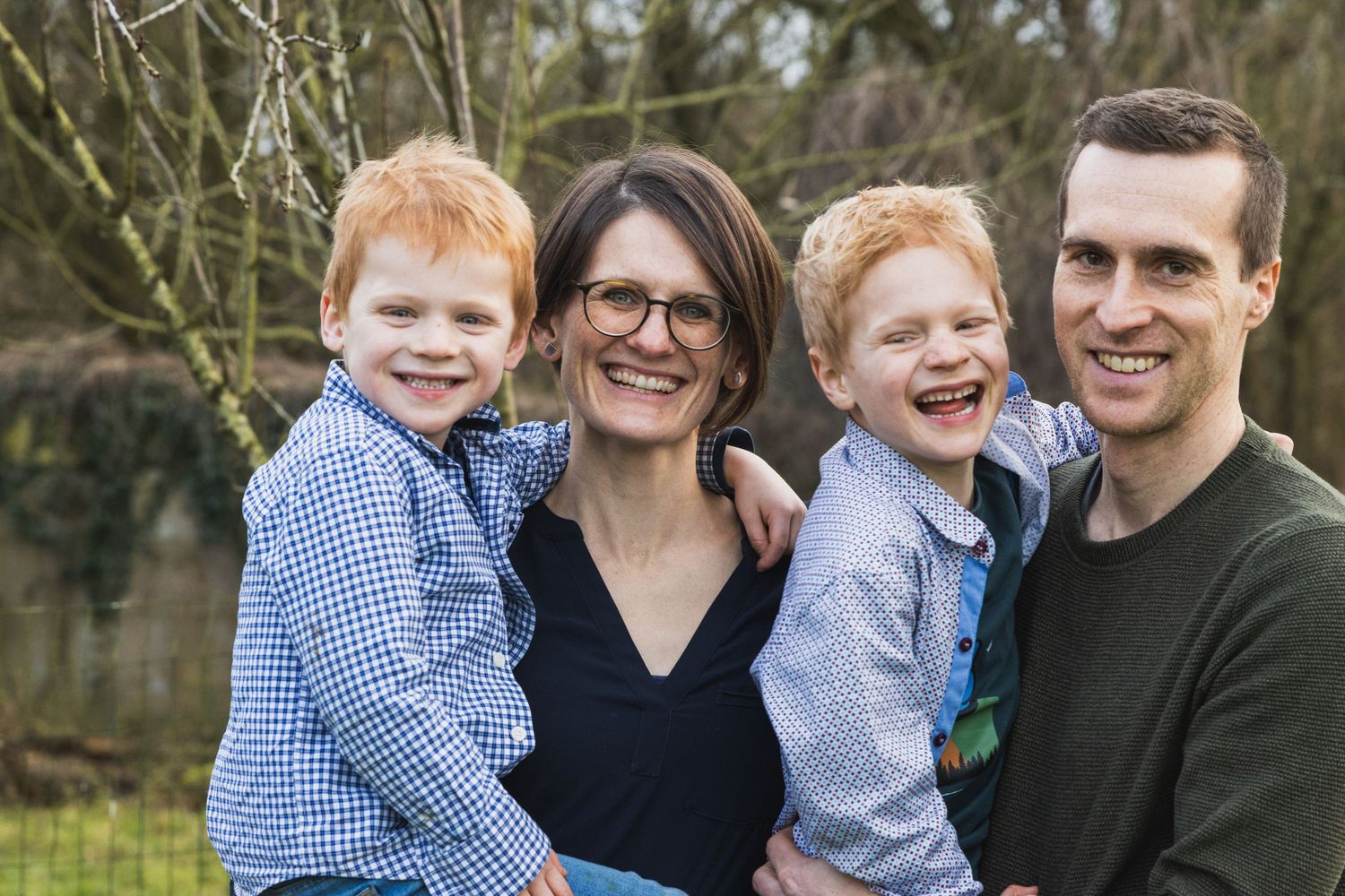 Een gezinsfoto van een vrouw en man met hun twee zonen. Ze lachen allemaal.