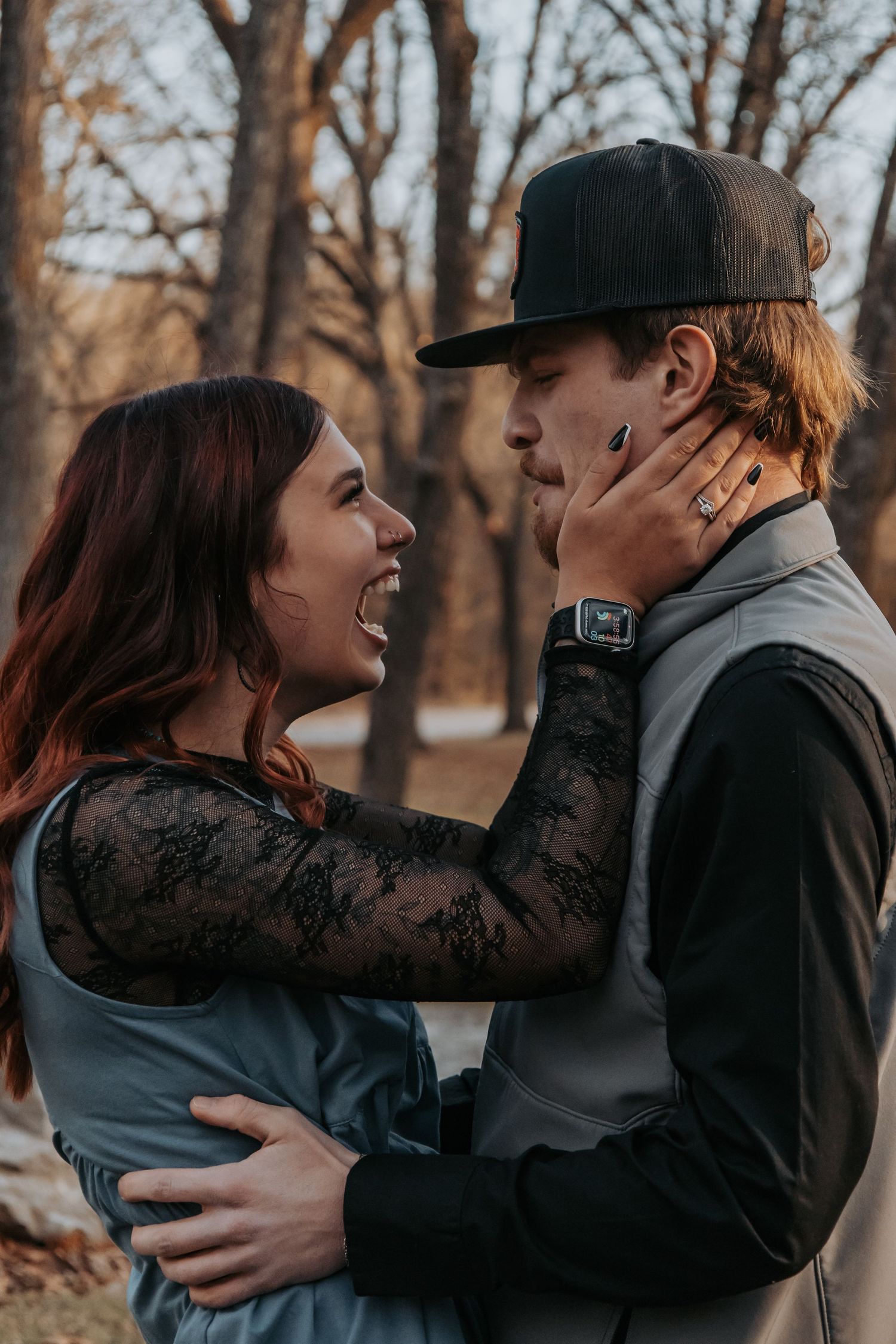 A romantic couple embraces and shares tender moments against a backdrop of bare winter trees.