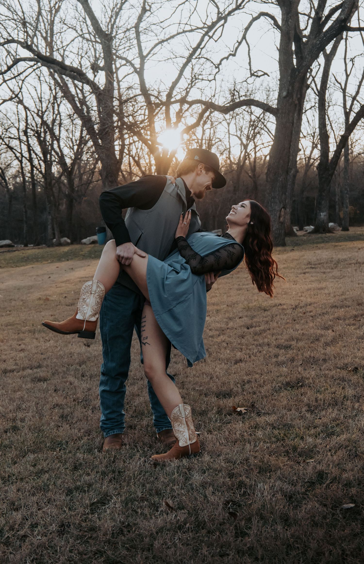 A couple dances together in a field at sunset, creating a romantic silhouette against the bare winter trees.