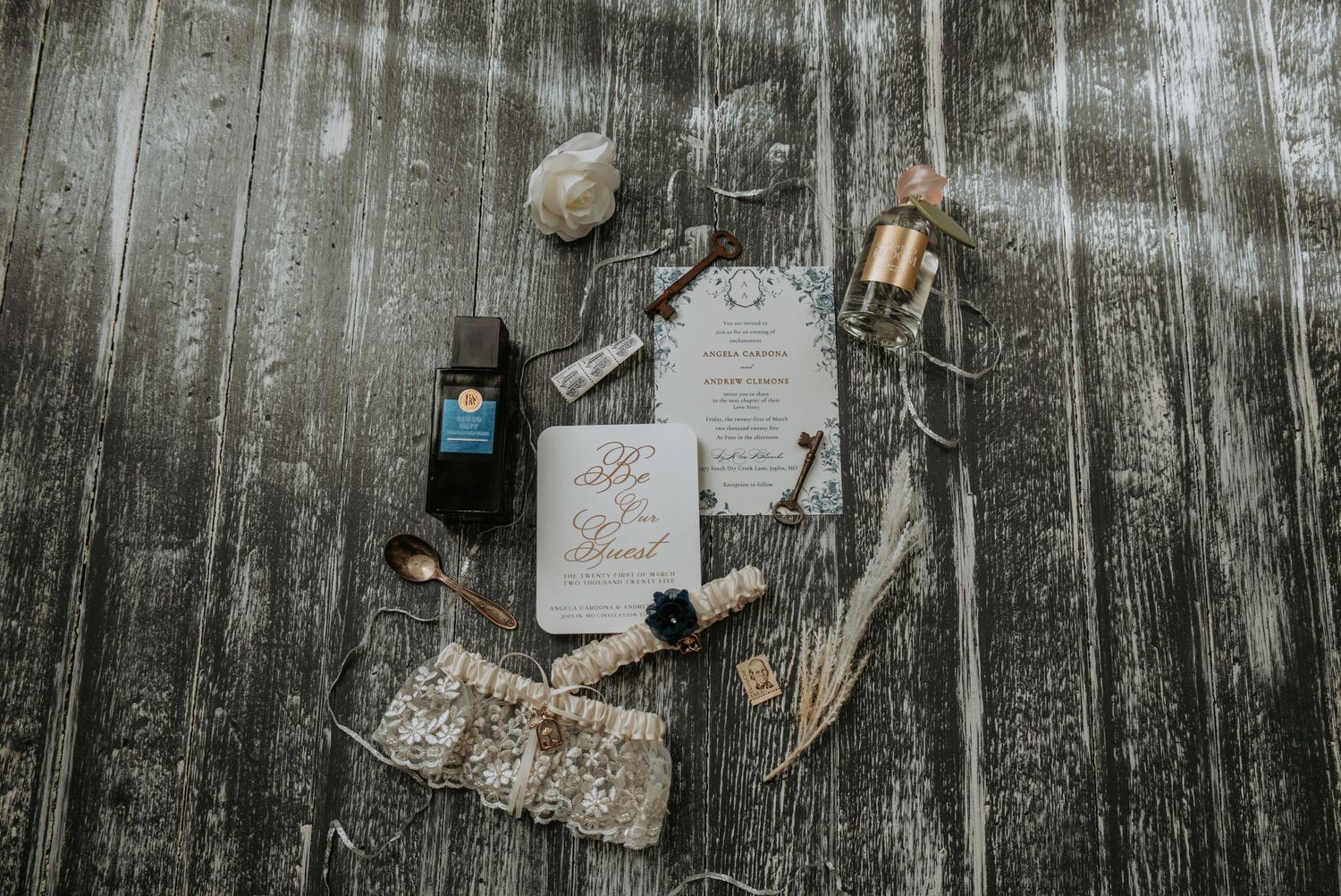 Rustic wedding invitation flatlay with vintage decor elements and calligraphy on weathered wood background.