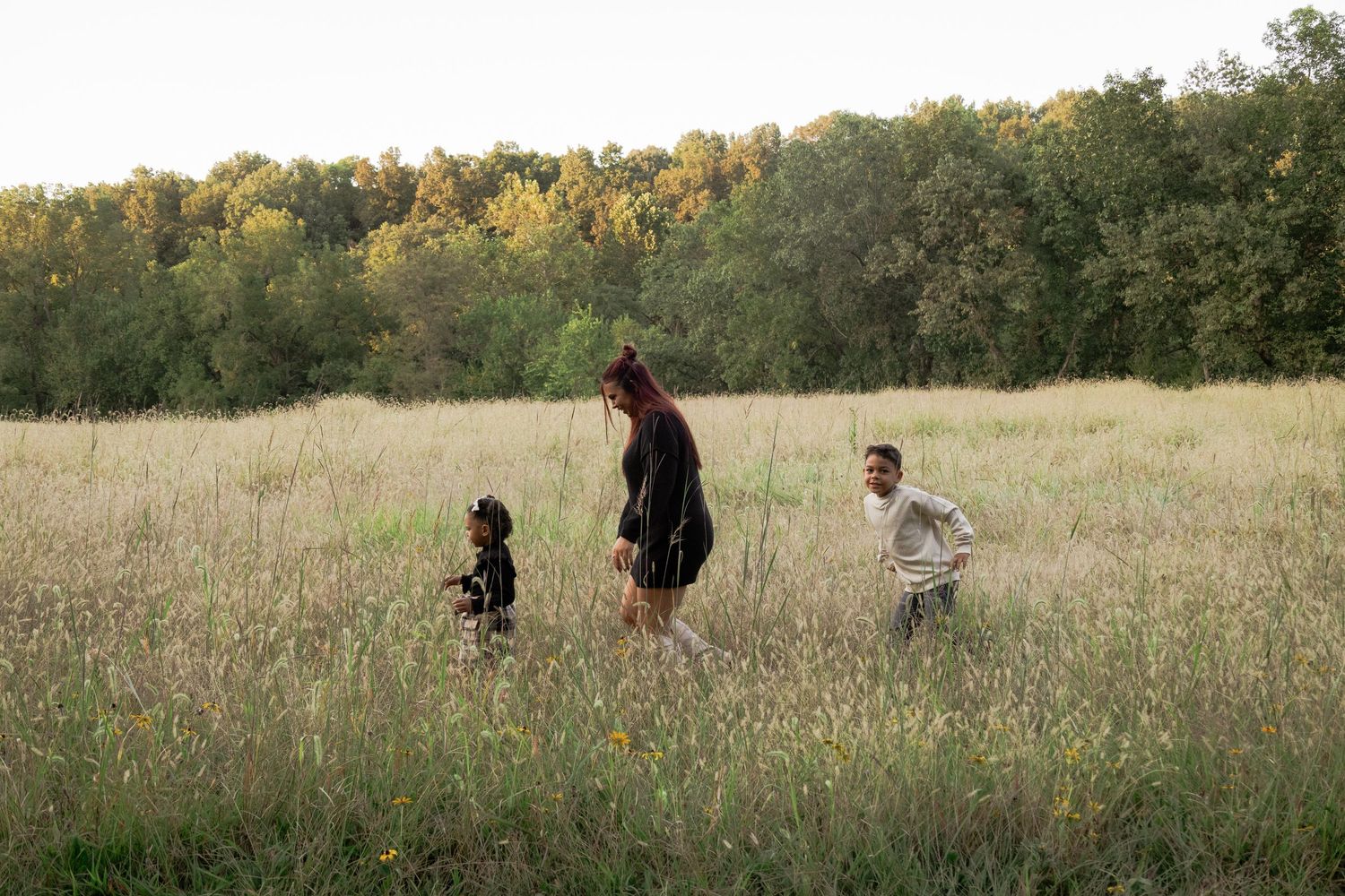 Wedding party walking through a golden autumn field during sunset photography session.