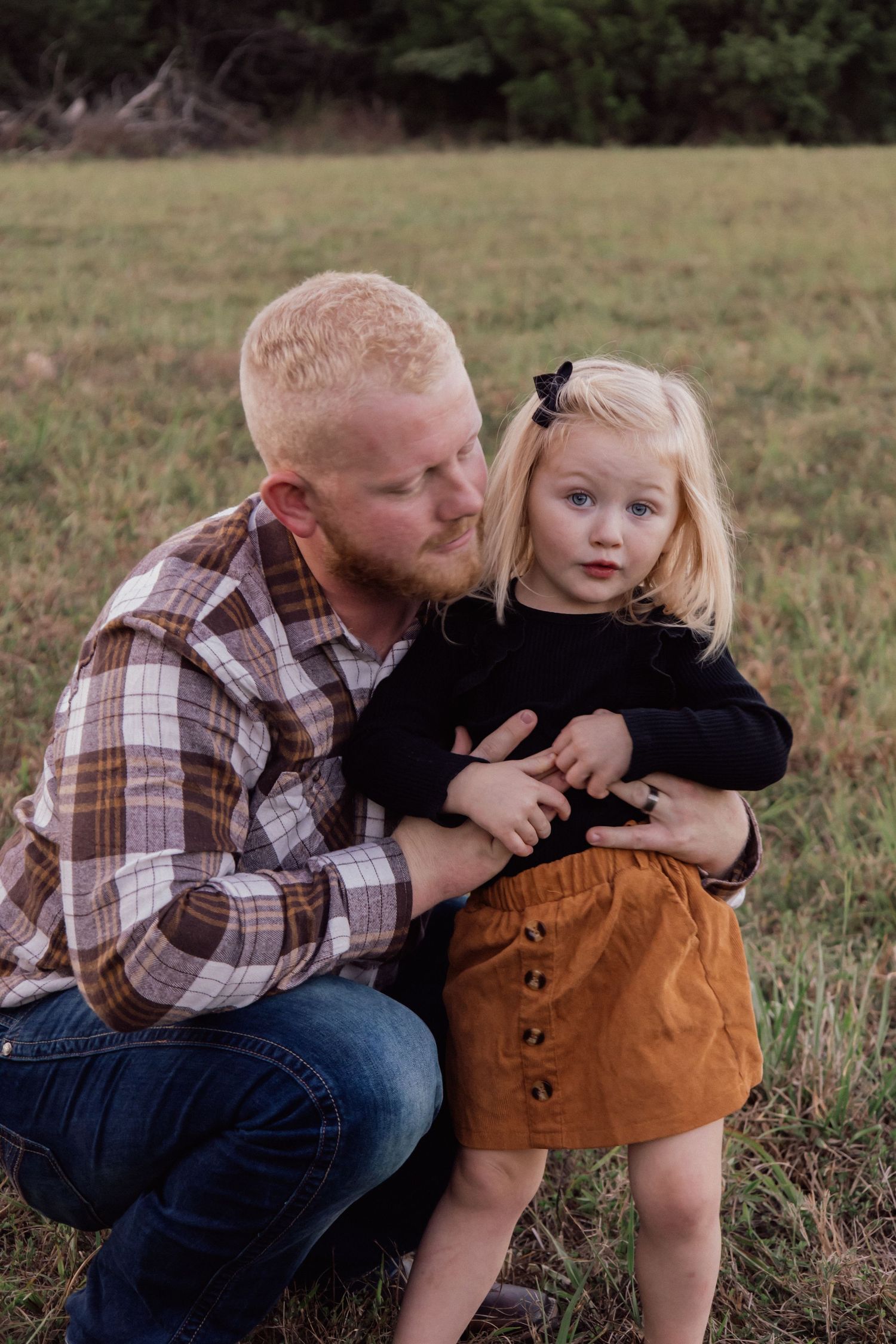 Playful family moment captured in a grassy field during a photo session.