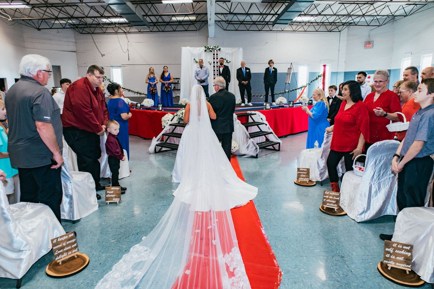 People gather in a large indoor space with white and red decorative elements for a special event.