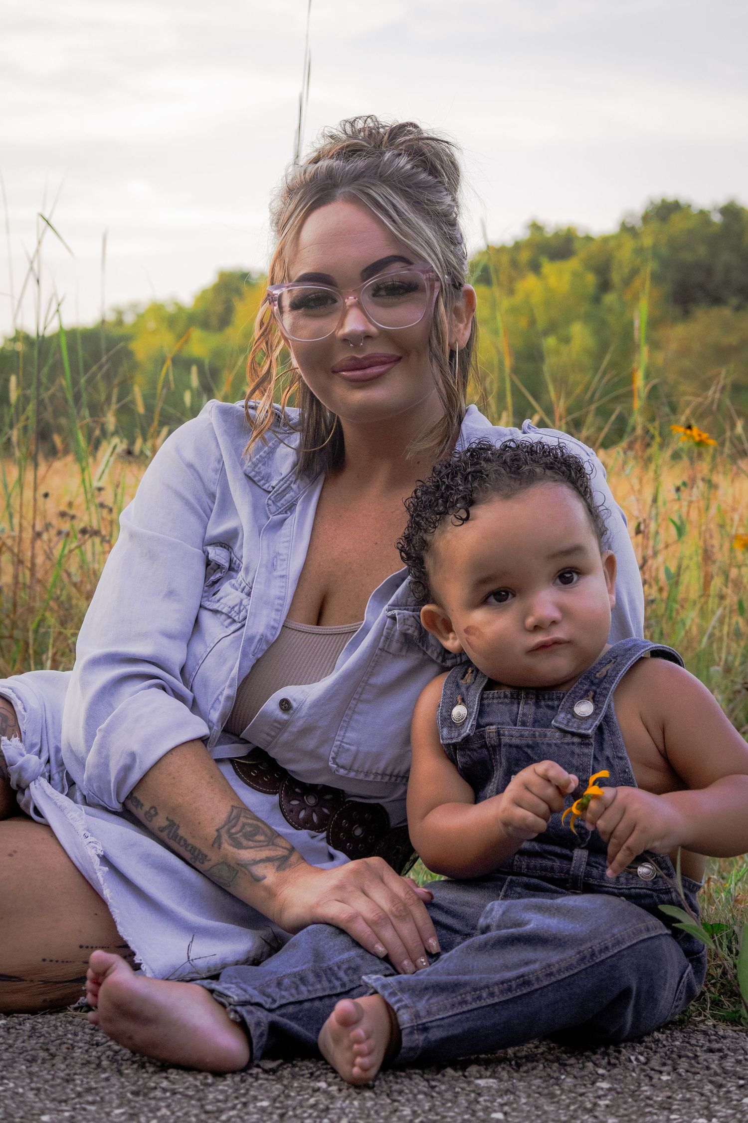 A heartwarming outdoor photoshoot in a wildflower field with denim overalls and a white top on a sunny day.