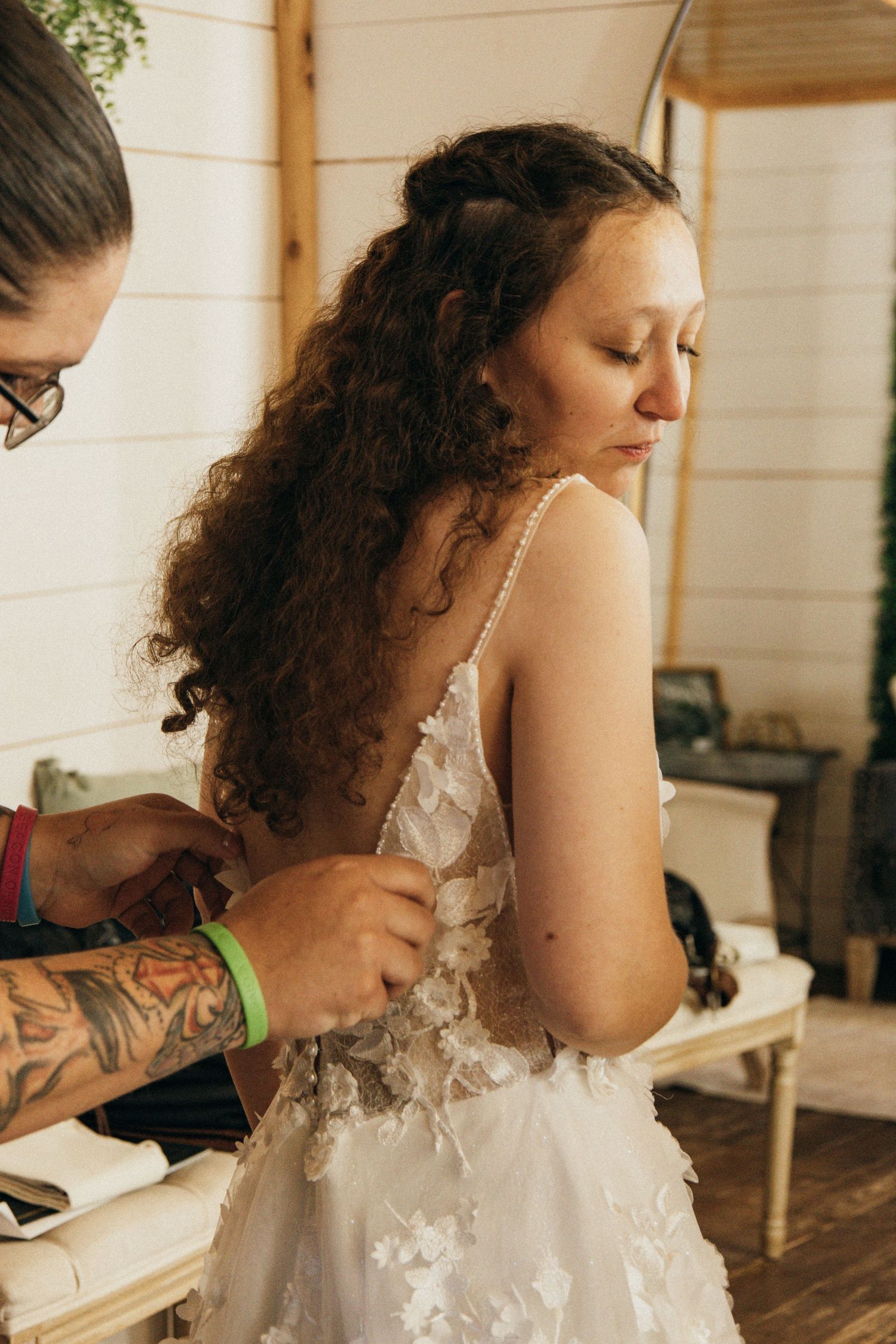 A series of photos showing someone getting a traditional white lace wedding dress laced up from behind.