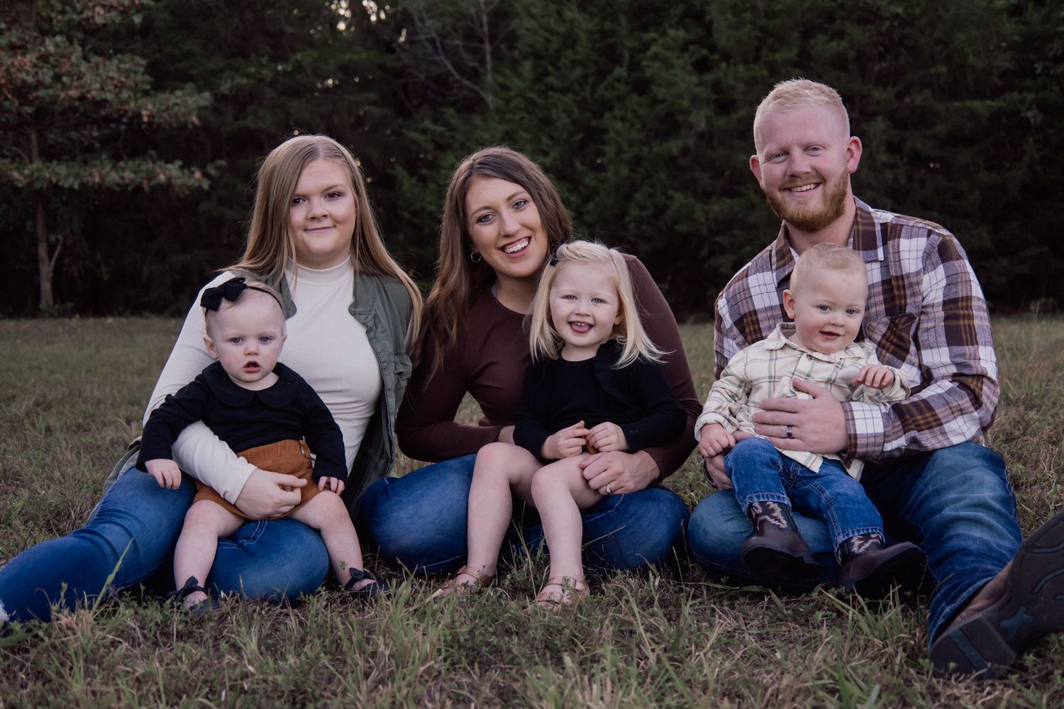 Family group lounging together on grass during an outdoor photo session.
