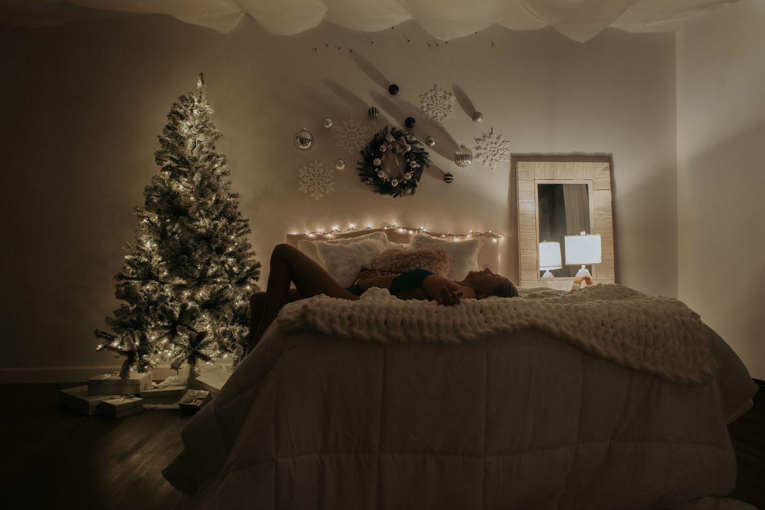 A cozy living room decorated for Christmas with a lit tree, string lights, and comfortable seating arrangements.