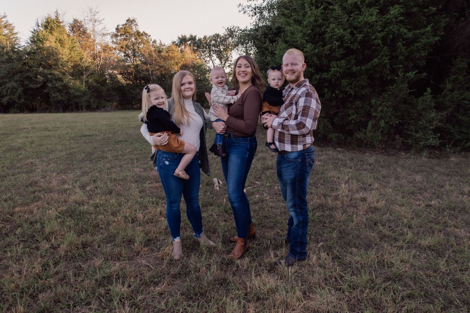 Family walking together on a grassy hillside during golden hour.