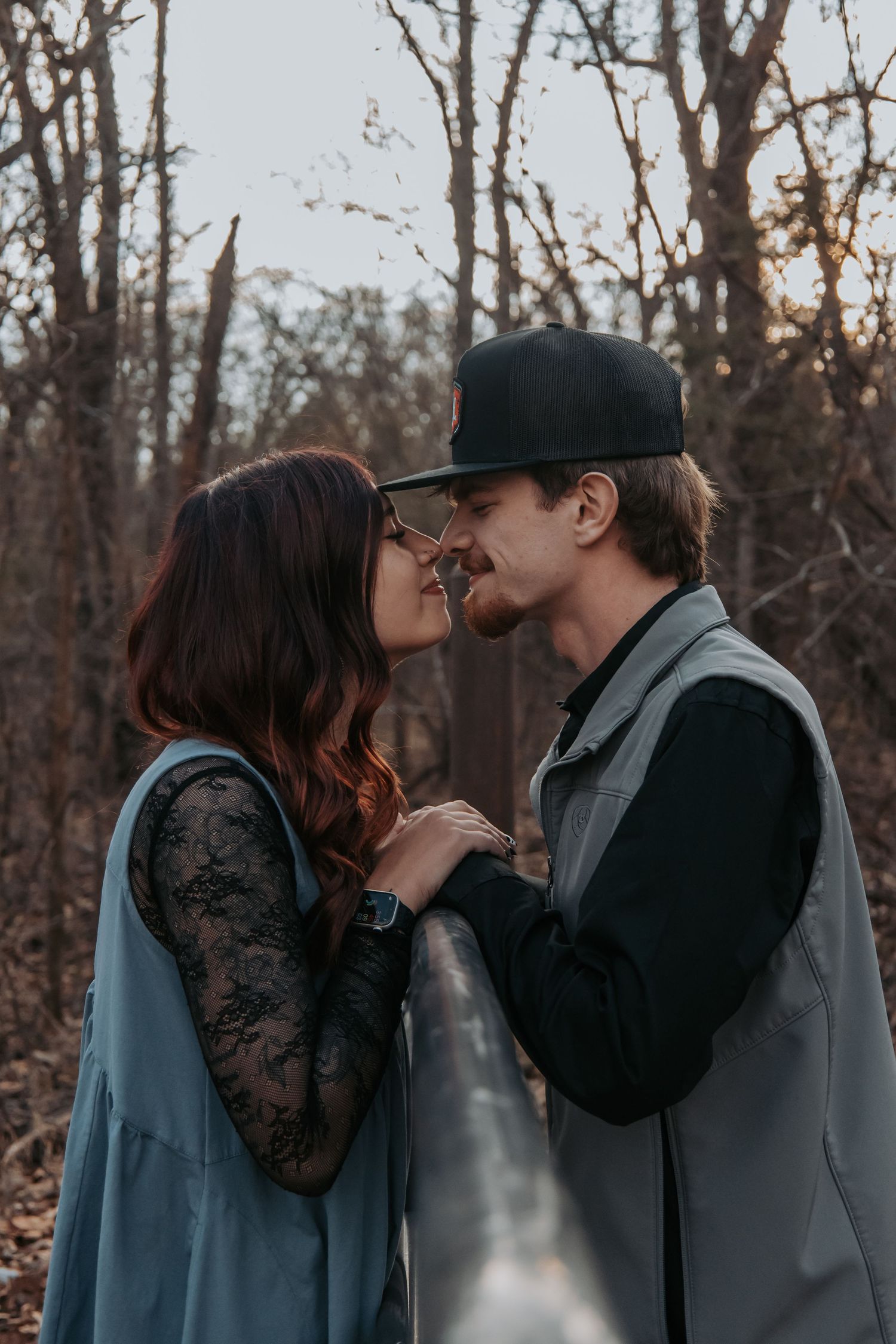 A romantic couple shares intimate kisses in a series of four progressive photos taken in a wooded outdoor setting.
