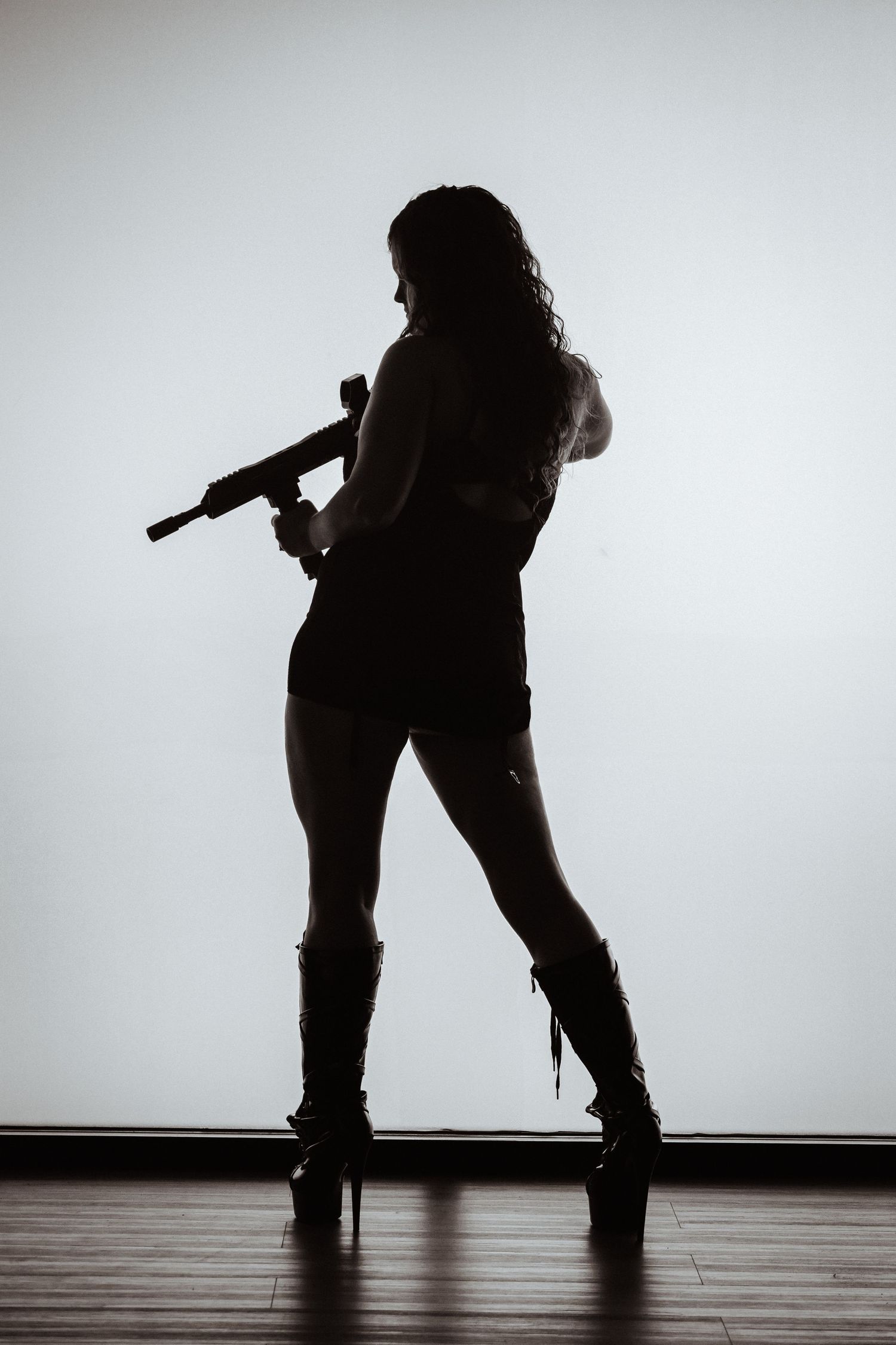 Dramatic silhouettes show a figure in five different poses against a white background on wooden flooring.