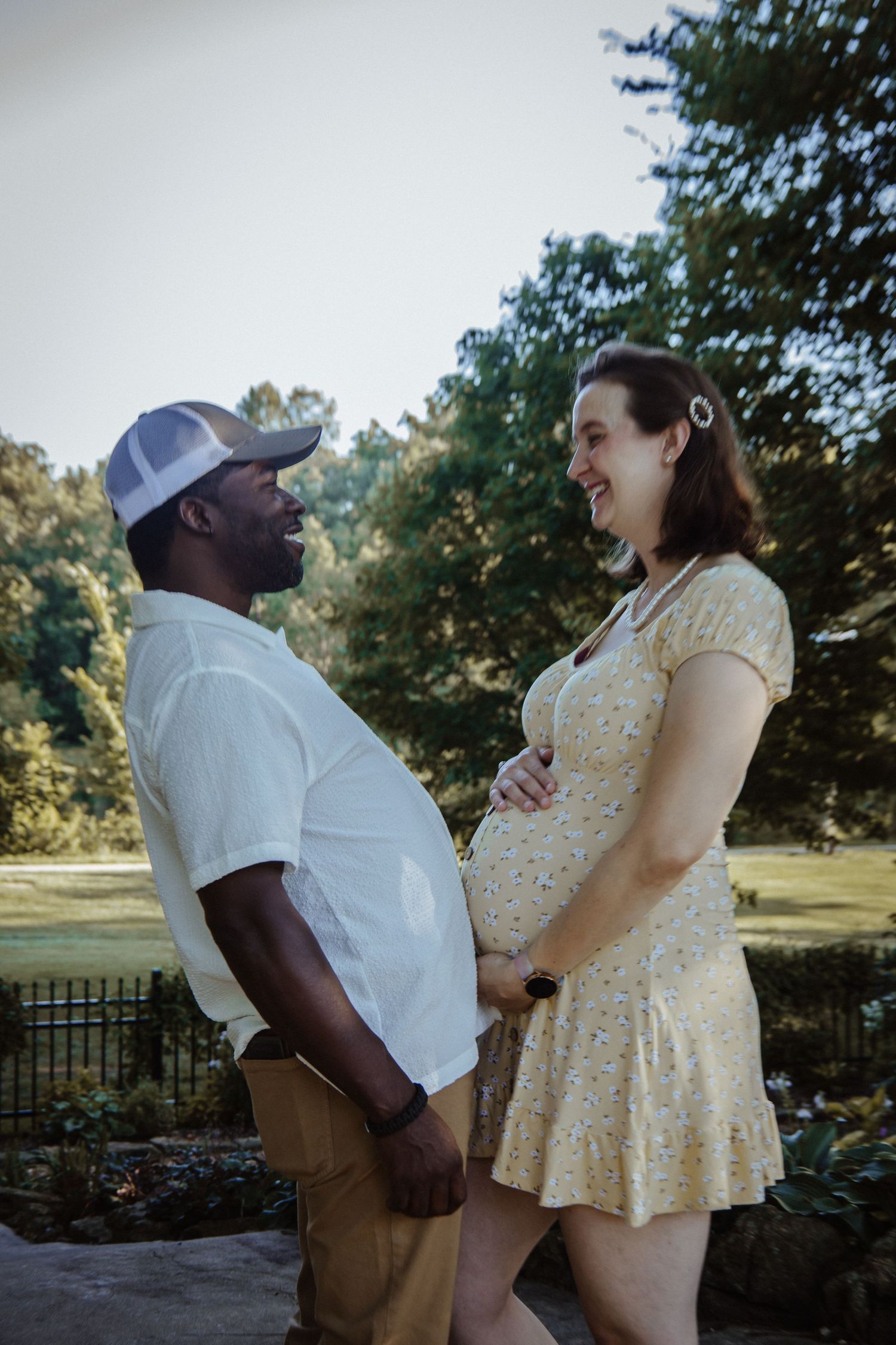 A couple shares joyful moments together outdoors in a park setting while wearing casual summer attire.