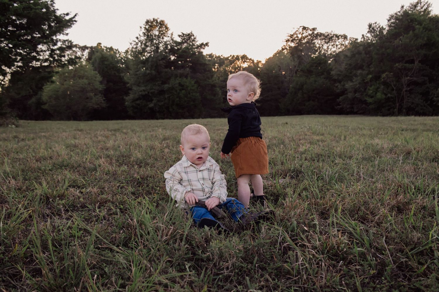 People enjoying quality time together on grass field at dusk with trees in background.