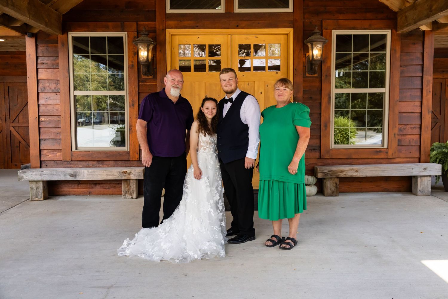 A group gathers at a rustic wooden lodge venue for a wedding celebration.
