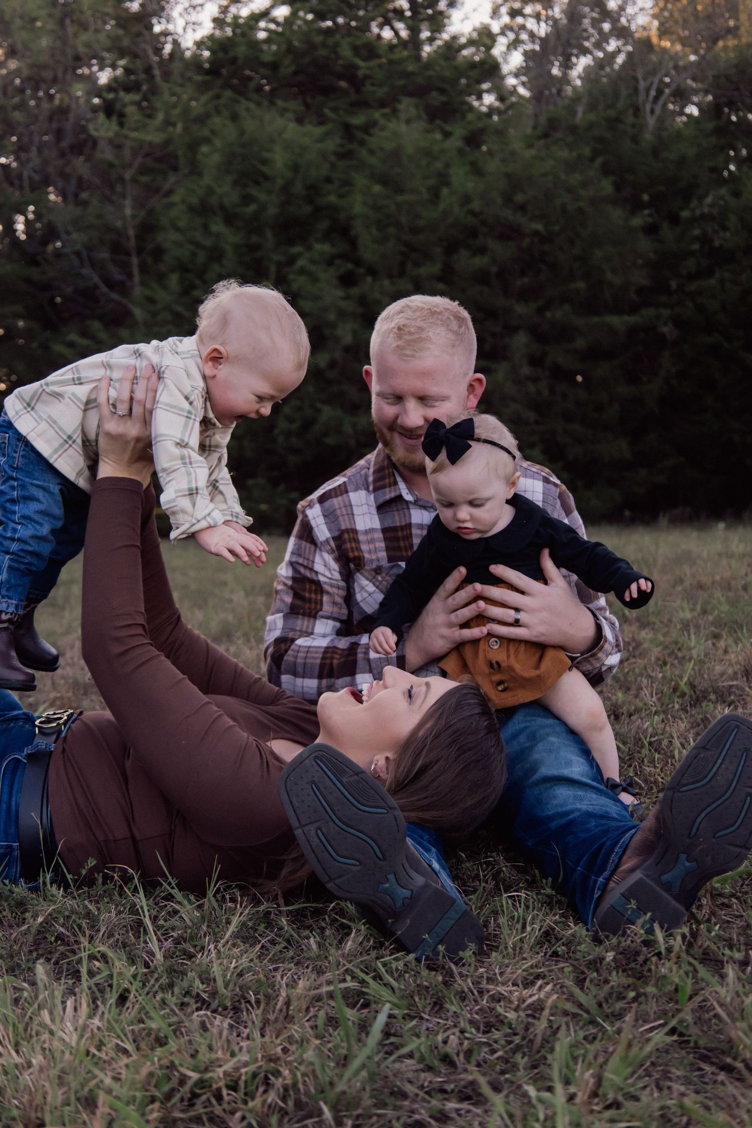 A family lying in grass shares playful moments together during an outdoor photo session.